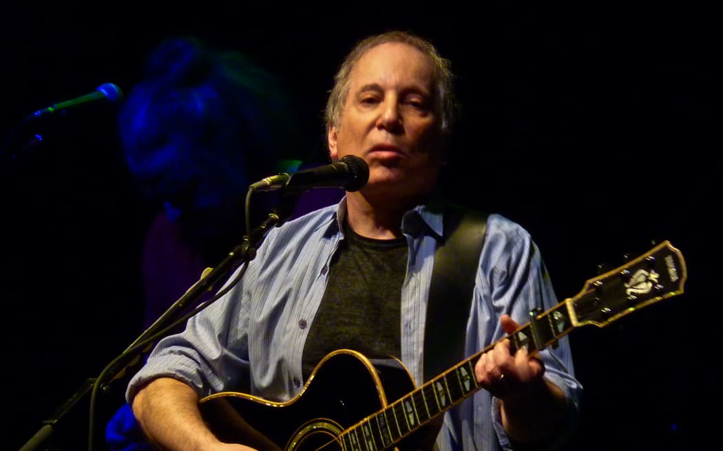 Musician Paul Simon performing with guitar