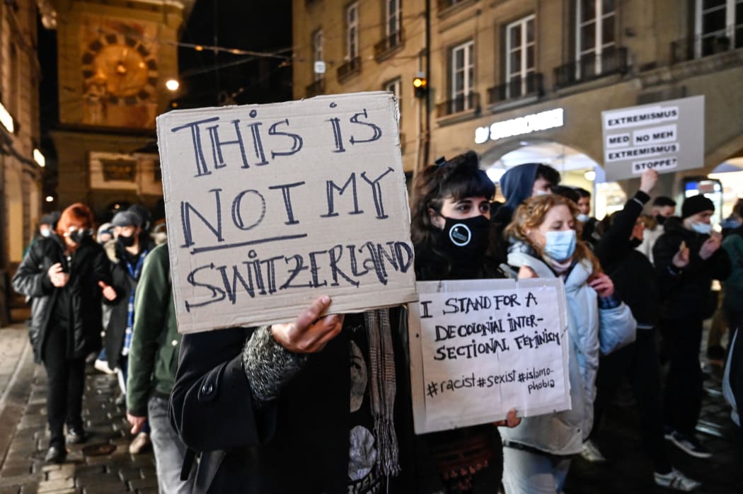 People hold signs during a protest hours after Switzerland has narrowly voted in favour of banning face coverings in public, including the burka or niqab worn by Muslim women.