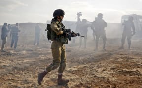 An Israeli soldier walks amidst the smoke from teargas canisters during a demonstration against the construction of Jewish settlements in the village of Ein al-Beida.
