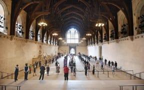A handout photograph released by the UK Parliament shows members of parliament queuing in Westminster Hall to vote.