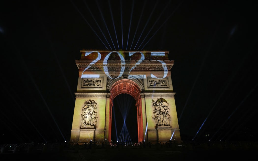 This photograph shows the illuminated Arc de Triomphe on the Avenue des Champs-Elysees in Paris early January 1, 2025, during New Year celebrations. (Photo by Thomas SAMSON / AFP) / RESTRICTED TO EDITORIAL USE