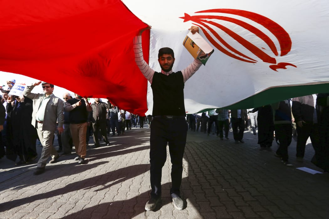 A pro-government demonstrator stands under an Iranian flag during a march in Iran's southwestern city of Ahvaz on January 3, 2018.