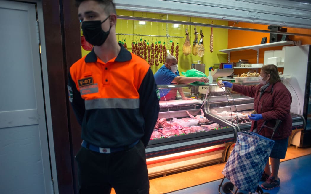 A woman wearing a face mask shops in a food market in Ronda on 13 April  2020 as some companies were set to resume operations.