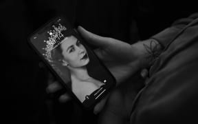 A person holds their phone with a screensaver of Queen Elizabeth II who died on September 9, 2022 in London, England.