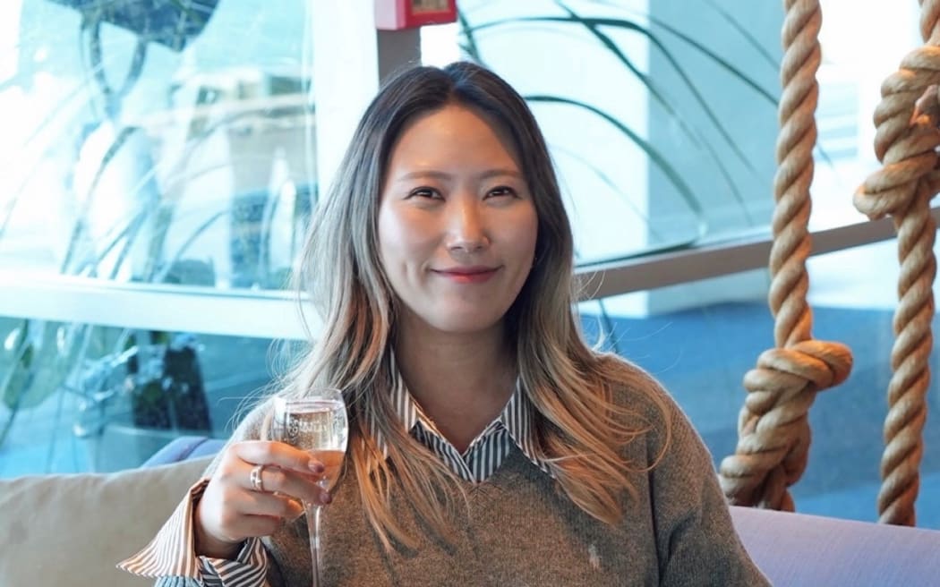 Auckland-based content creator Jasmine Kim smiling while holding a wine glass.
