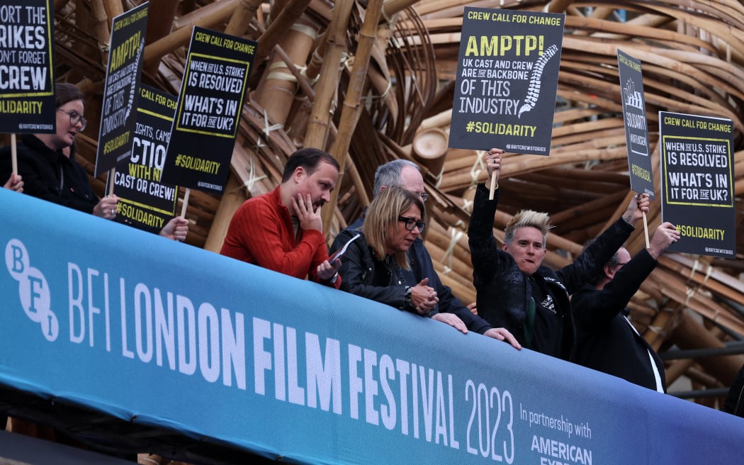 Demonstrators hold placards calling for change for the crews of UK TV and films productions, as they protest on the opening night Gala Premiere of the film "Saltburn" during the 2023 BFI London Film Festival in London, on October 4, 2023. American television and movie writers on Tuesday agreed to end a strike that lasted nearly five months and paralyzed Hollywood after reaching a pay deal with production studios, the Writers Guild of America said. (Photo by Adrian DENNIS / AFP)