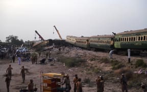 Security personnel and volunteers inspect the accident site following the derailment of a passenger train in Nawabshah on August 6, 2023. At least 28 people were killed August 6 when an express train derailed in southern Pakistan, the railway minister said, with an emergency declared at local hospitals struggling to deal with with dozens of injured. (Photo by ASIF HASSAN / AFP)