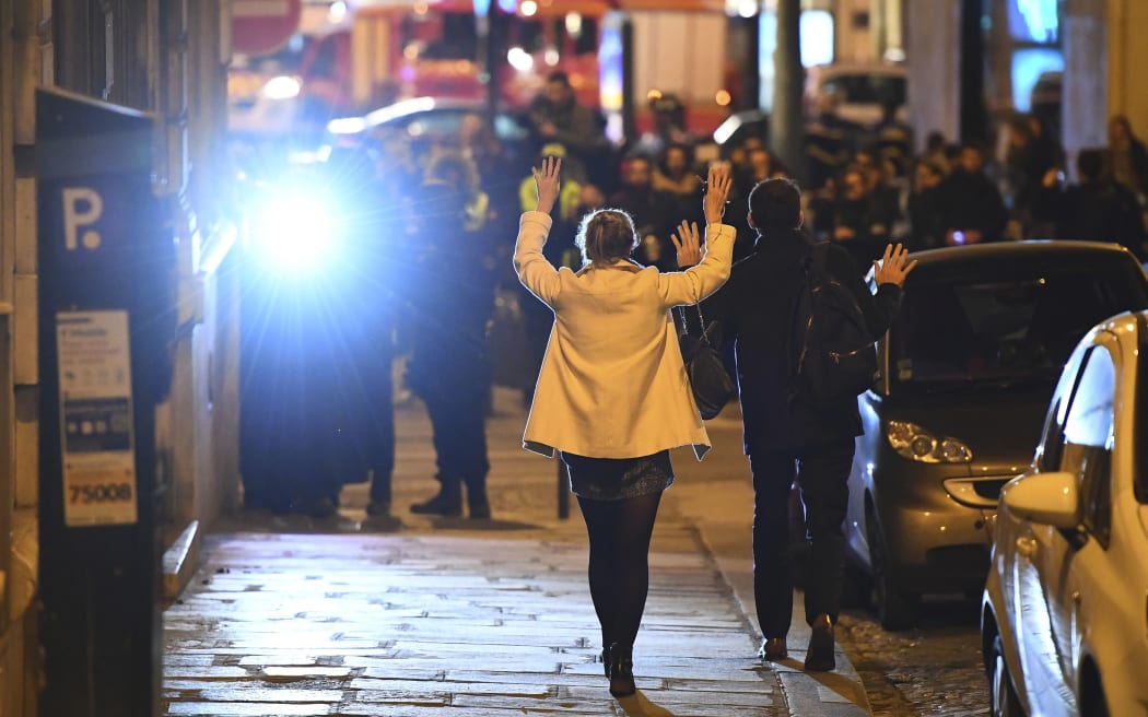 People hold their hands up as they walk towards police officers before being controlled near the site of a shooting at the Champs Elysees in Paris on April 20, 2017.