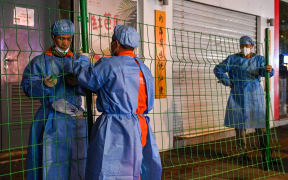 This photo taken late on October 7, 2022 shows workers erecting fencing around a neighbourhood in lockdown in Shanghai's Changning district, after new Covid-19 cases were reported. (Photo by Hector RETAMAL / AFP)