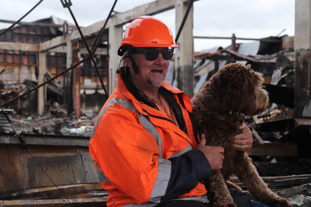 Building owner Jason Wray beside his fire ravaged property with his dog Bella.