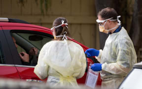 Staff at a COVID-19 coronavirus clinic conduct a test on a man inside his car outside a COVID-19 coronavirus clinic in Lower Hutt, near Wellington, on April 20, 2020.