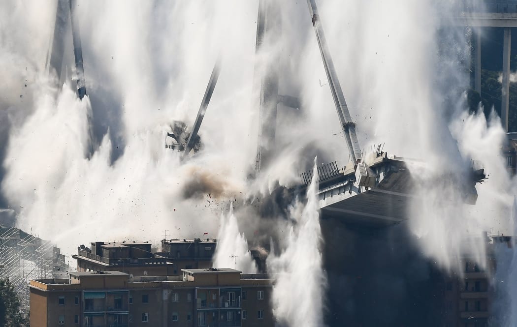 The bridge's deck collapses in a cloud of smoke and water after explosive charges blew up the eastern pylons of Genoa's Morandi motorway bridge on June 28, 2019 in Genoa.