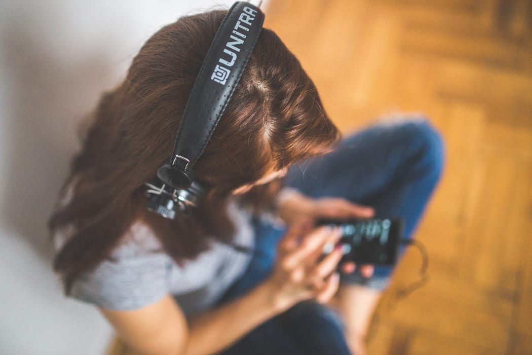 Woman listening via headphones and smartphone