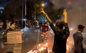 A picture obtained by AFP outside Iran shows shows a demonstrator raising his arms and makes the victory sign during a protest for Mahsa Amini, a woman who died after being arrested by the Islamic republic's "morality police", in Tehran on September 19, 2022.
