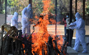 Family members and relatives wearing protective gear prepare a funeral pyre to cremate a Covid-19 victim in New Delhi.