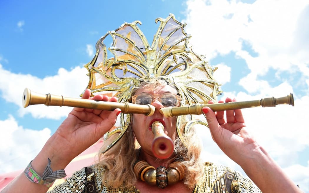 A performer plays three recorders simultaneously at the Glastonbury festival near the village of Pilton in Somerset, south-west England, on June 25, 2022. - More than 200,000 music fans descend on the English countryside this week as Glastonbury Festival returns after a three-year hiatus. The coronavirus pandemic forced organisers to cancel the last two years' events, and those going this year face an arduous journey battling three days of major rail strikes across the country. (Photo by ANDY BUCHANAN / AFP)