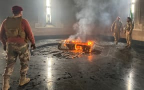 Rebel fighters standing next to the burning gravesite of Syria's late president Hafez al-Assad at his mausoleum in Latakia province, after it was stormed by opposition factions.