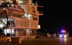 Passengers of the COVID-19 coronavirus-stricken Australian liner Greg Mortimer disembark in personal protective equipment from the cruise ship at Montevideo's port from where Australian and New Zealander passengers will be directly escorted to the international airport