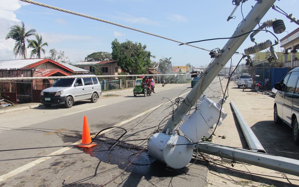 Motorists speed past a fallen electric pylon damaged at the height of Typhoon Phanfone in Balasan town in Iloilo province on December 26, 2019.