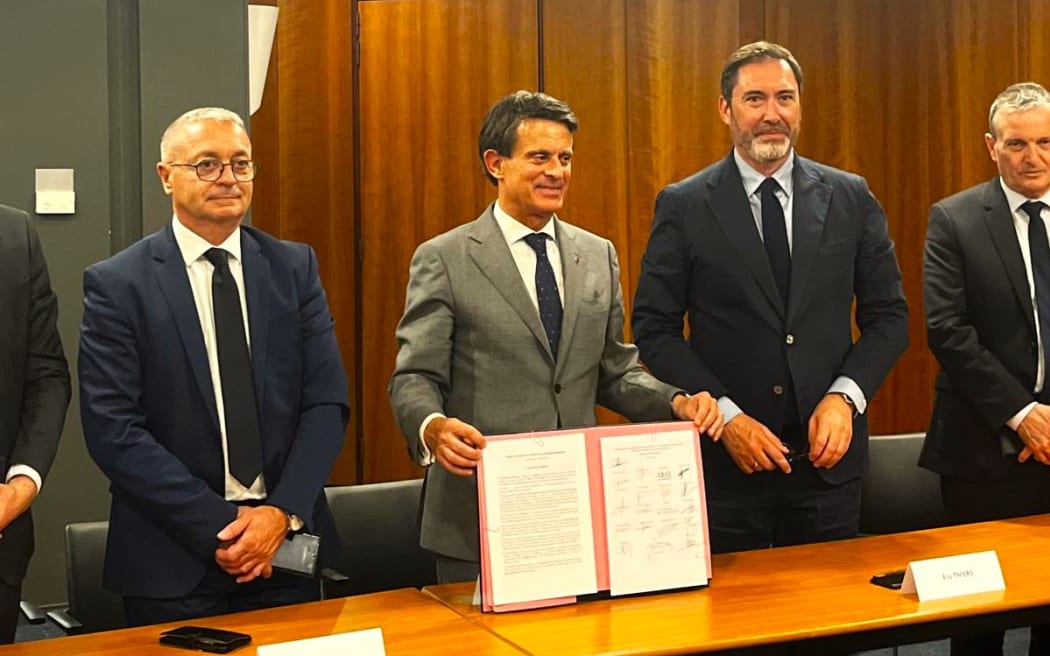 French Minister for Overseas Manuel Valls (centre) shows signatures on the last page of New Caledonia’s new agreement