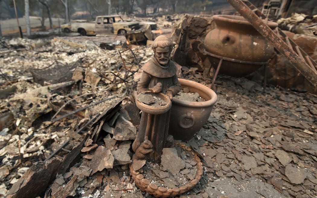 A statue amidst rubble from a burned out home.