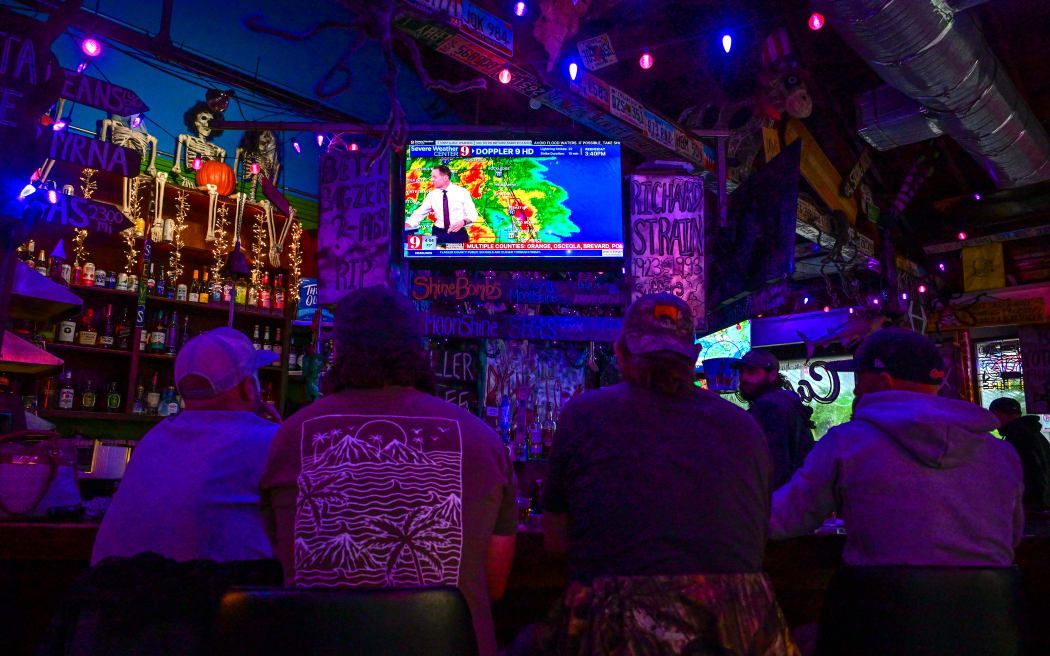 Bar patrons watch the weather news in Orlando, Florida, on 9 October 2024 while Hurricane Milton races towards Florida. - Many Florida residents have fled, but some battened down the hatches, in the final hours Wednesday before Hurricane Milton pummels the state, as government relief efforts were dragged into the thick of the White House race. (Photo by GIORGIO VIERA / AFP)