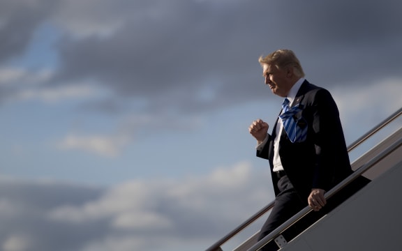 US President Donald Trump gives one of his habitual fist-pumping gestures to a gathered crowd as he exits Air Force One.