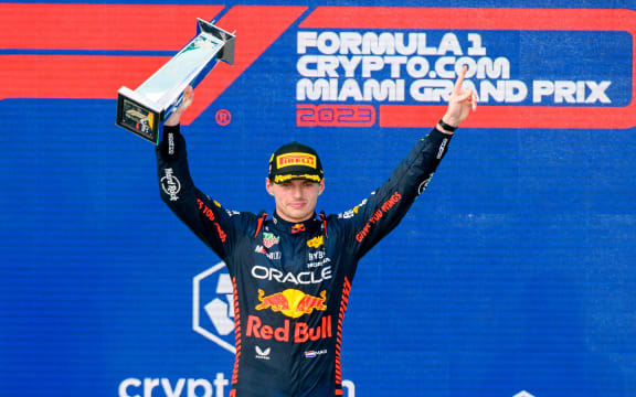 Oracle Red Bull Racing driver Max Verstappen celebrates winning the 2023 Miami GP as he holds the first place trophy on the podium.
