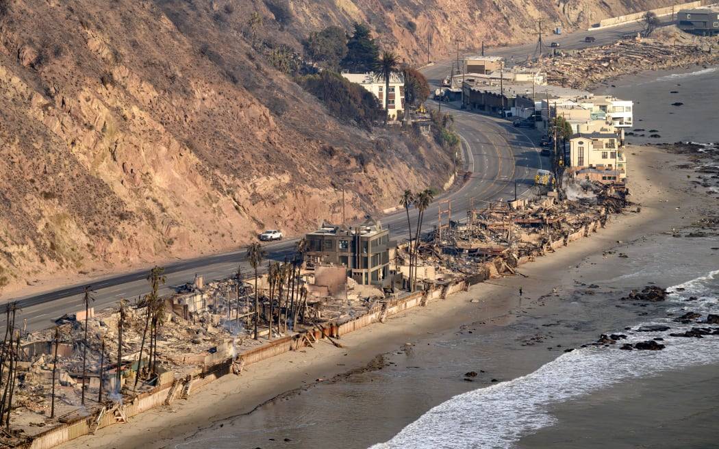 In this aerial view taken from a helicopter, burned homes are seen during the Palisades fire in the Malibu area of Los Angeles county, California on January 9, 2025. Massive wildfires that engulfed whole neighborhoods and displaced thousands in Los Angeles remained totally uncontained January 9, 2025, authorities said, as US National Guard soldiers readied to hit the streets to help quell disorder. Swaths of the United States' second-largest city lay in ruins, with smoke blanketing the sky and an acrid smell pervading almost every building. (Photo by JOSH EDELSON / AFP)
