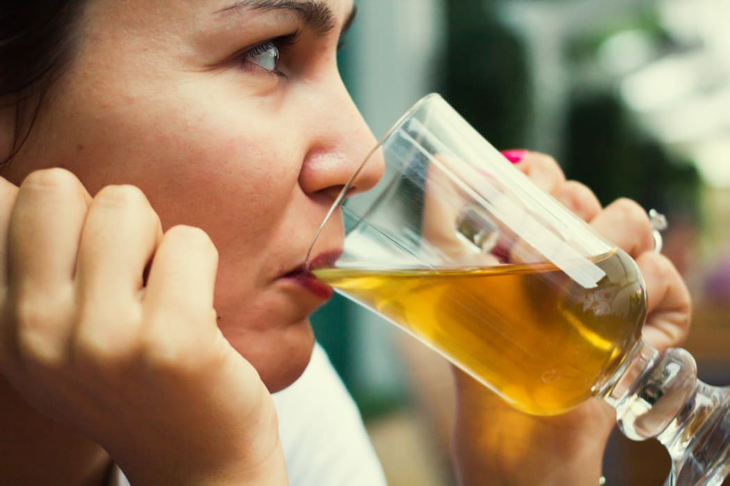 A woman drinks a glass of beer at a restaurant (file)