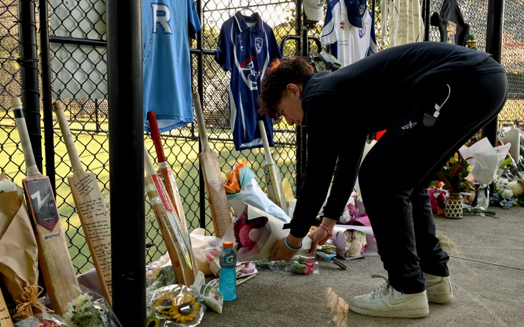 A young man lays flowers at the cricket nets in memory of 17-year-old Australian cricketer Ben Austin, who died after a cricket accident in Melbourne. (Photo by William WEST / AFP)