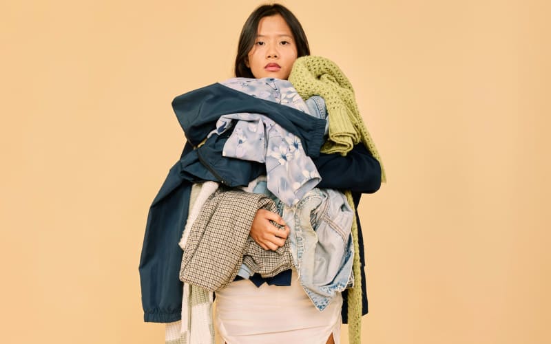 A woman holding a bunch of clothes.