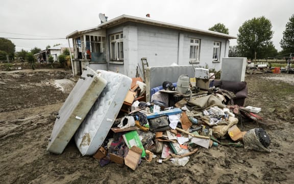 Debris piled up in front of a damaged house in Wairoa