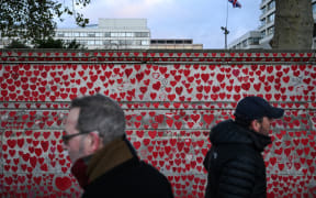 People walk past the National Covid Memorial Wall, dedicated to those lost in the United Kingdom from Covid, in central London on November 20, 2025, ahead of the publication of a new report on government decision-making during the pandemic. The UK's Covid-19 lockdowns were "too little, too late" and could have been avoided if restrictions were put in place sooner, an inquiry into the country's response to the global health emergency concluded on November 20. (Photo by Chris J Ratcliffe / AFP)