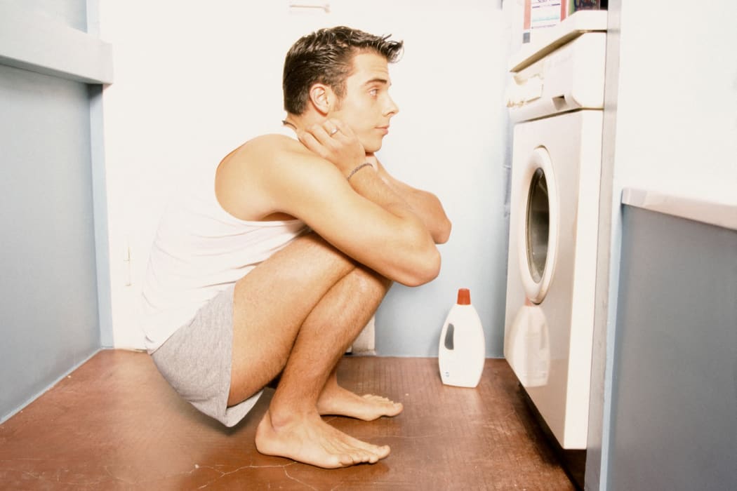 Teenage boy watching washing machine (Photo by ANSGAR WERRELMANN / Image Source / Image Source via AFP)