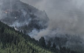A helicopter flies a monsoon bucket of water onto an area of the Port Hills fires during the Christchurch fires last Thursday. 16 February 2017