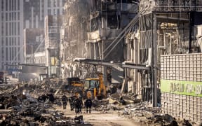 Ukrainian firefighters and servicemen work next to a digger amid the rubble of the Retroville shopping mall, a day after it was shelled by Russian forces, Kyiv, 21 March 2022.