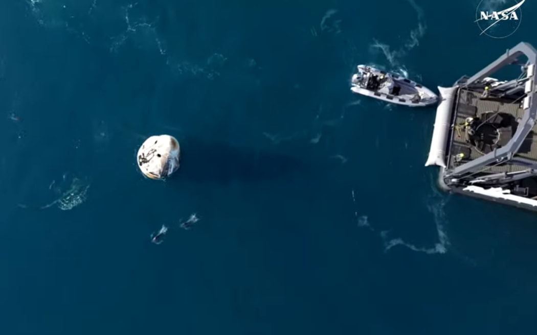 Nasa dragon capsule seen in the water after splashing down off Florida coast, and pulled onto recovery capsule