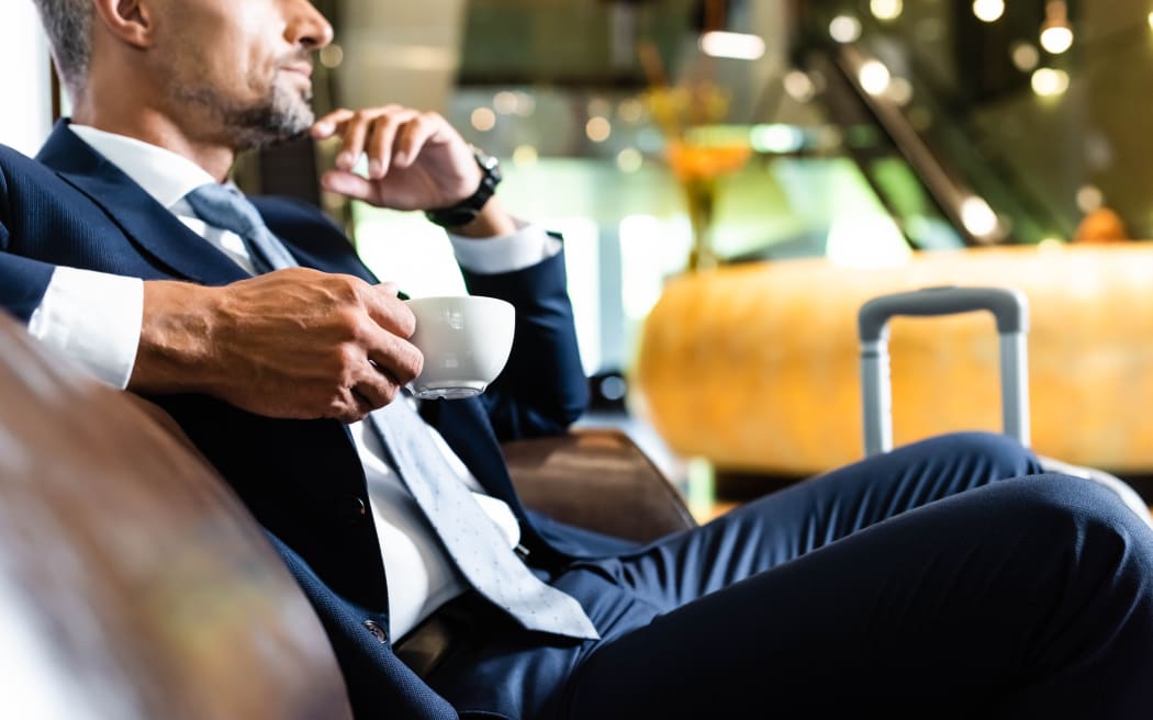 Cropped view of businessman in suit holding cup