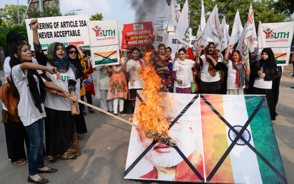 Activists of the Youth Forum for Kashmir group shout slogans as they burn a picture of Indian Prime Minister Narendra Modi and the Indian flag during a protest in Lahore.