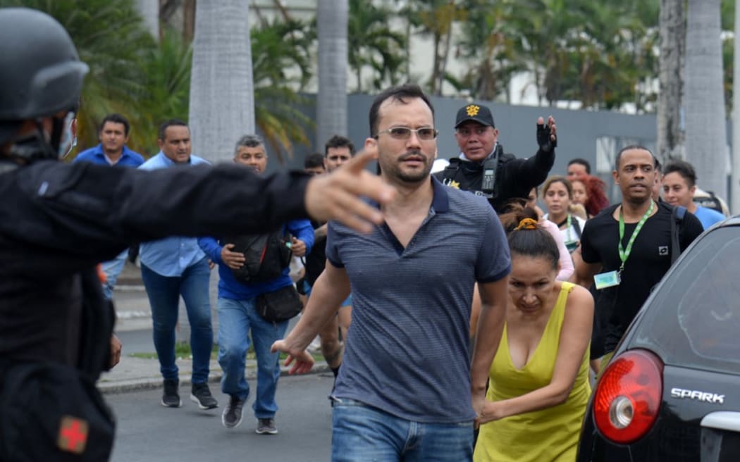 People is helped out of the premises of Ecuador's TC television channel after unidentified gunmen burst into the state-owned television studio live on air on January 9, 2024, in Guayaquil, Ecuador, a day after Ecuadorean President Daniel Noboa declared a state of emergency following the escape from prison of a dangerous narco boss. Gunshots rang out on live TV in violence-torn Ecuador as armed men carrying rifles and grenades stormed the studio shortly after gangsters vowed a "war" against the president's plans to reclaim control from "narcoterrorists". (Photo by STRINGER / AFP)
