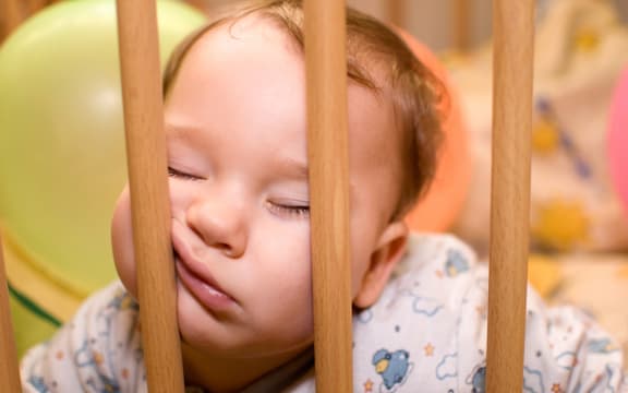 Baby sleeps with funny face in the playpen