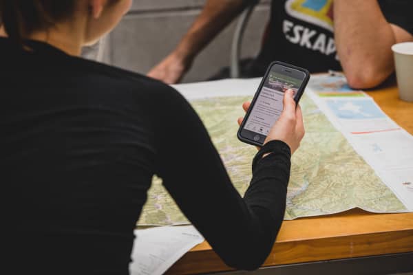 Person looking at track info on phone, with map on table in front of them.