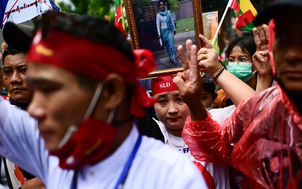 Protesters show the three finger salute and hold photos of detained Myanmar civilian leader Aung San Suu Kyi during a demonstration against the Myanmar military junta’s execution of four prisoners, outside the Myanmar Embassy in Bangkok on 26 July, 2022.