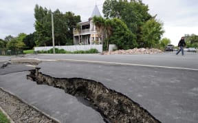 A woman walks across a broken street in the days following the fatal February 22 earthquake.