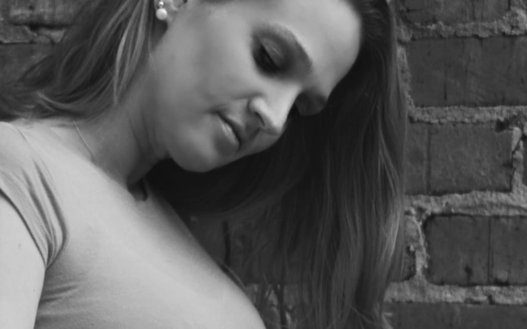 A young pregnant woman holds her belly
