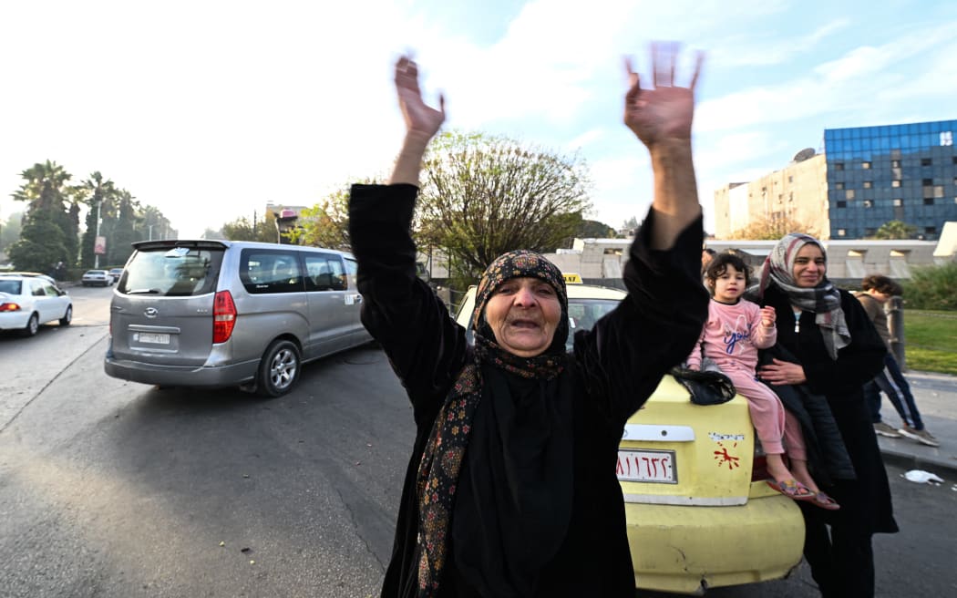 An elderly woman celebrates at Umayyad Square in Damascus on December 8, 2024. - Islamist-led rebels declared that they have taken Damascus in a lightning offensive on December 8, sending President Bashar al-Assad fleeing and ending five decades of Baath rule in Syria. (Photo by LOUAI BESHARA / AFP)