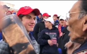 Student Nick Sandmann stands close staring at Omaha elder Nathan Phillips.