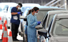 Health officials collect COVID-19 swab tests at a drive-through testing site on Bondi beach in Sydney.