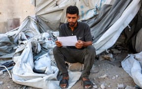 A man reads one of the leaflets dropped by the Israeli military on Gaza City, urging evacuation south to al-Mawasi.